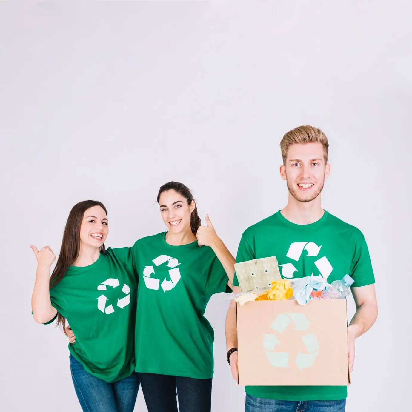 Радостный мужчина держит картонную коробку с предметами для переработки перед женщинами, показывающими большой палец вверх.